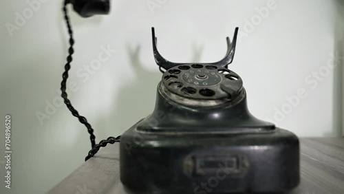 A person dials a number on a vintage telephone. Сalling with black retro phone. Man picks up handset on old phone and turns number plate of device. Close-up Dusty Retro Rotary Landline Phone photo