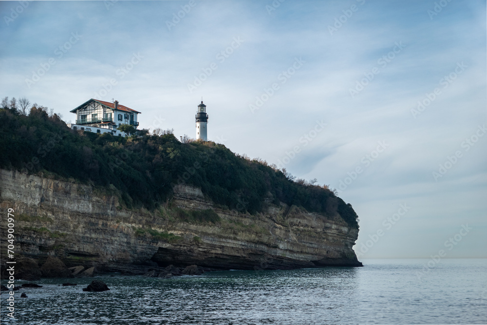 Falésia ou elevação rochosa com um farol e uma casa lá no alto junto à praia de Petite chambre d'amour  em Biarritz no País Basco, França
