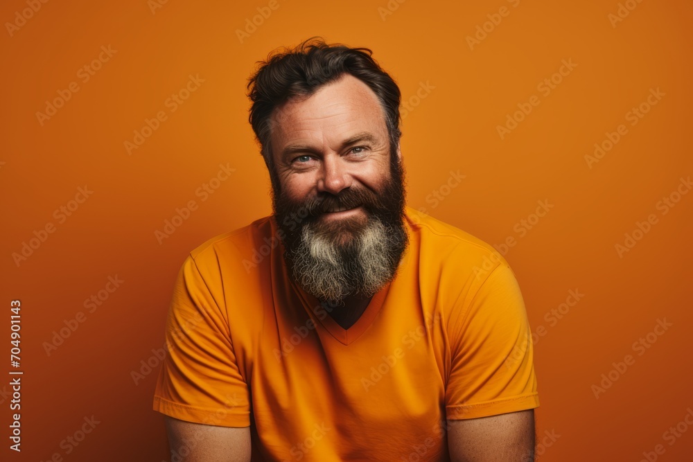 Portrait of a bearded man in orange t-shirt over orange background. Portrait of a bearded man in orange t-shirt over orange background.