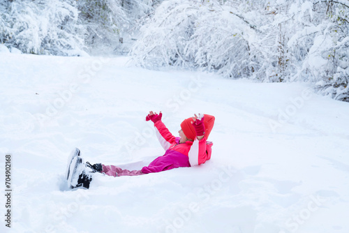Happy kid  lying in snow and playing  in winter nature