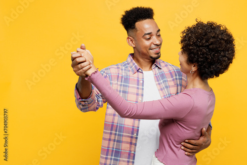 Young romantic happy smiling couple two friends family man woman of African American ethnicity wears purple casual clothes dancing together on party isolated on plain yellow orange background studio. photo