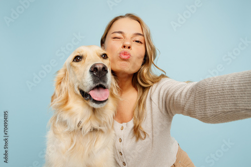 Close up young owner woman with her best friend retriever dog wears casual clothes do selfie shot on mobile cell phone wink isolated on plain pastel light blue background. Take care about pet concept. photo