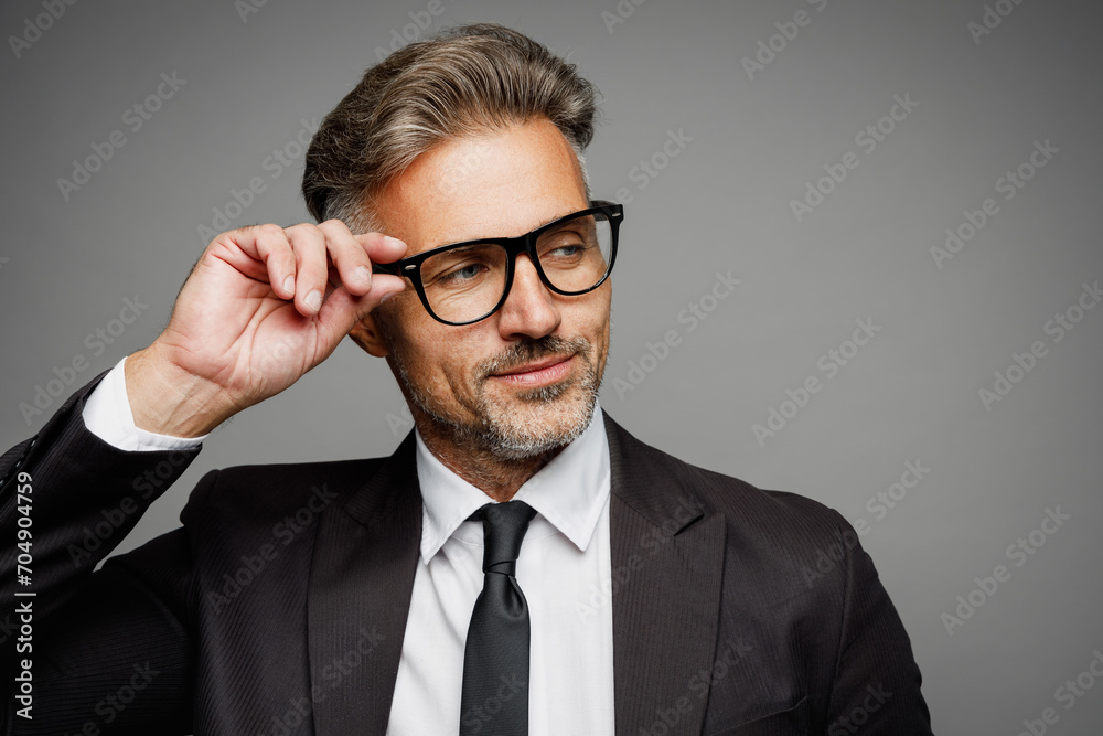 Close up adult successful employee business man corporate lawyer he wear classic formal black suit shirt tie work in office touch glasses look aside isolated on plain grey background studio portrait. Close up adult successful employee business man corporate lawyer he wear classic formal black suit shirt tie work in office touch glasses look aside isolated on plain grey background studio portrait.
