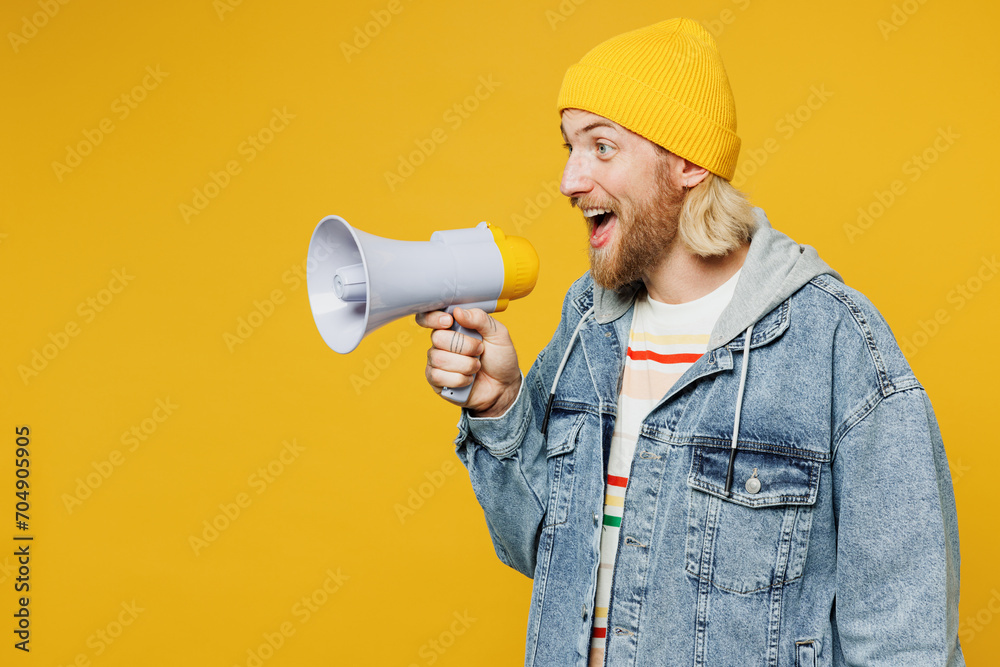 Young man he wears denim shirt hoody beanie hat casual clothes hold in hand megaphone scream announces discounts sale Hurry up isolated on plain yellow background studio portrait. Lifestyle concept. - obrazy, fototapety, plakaty 