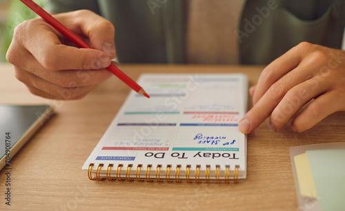 Close up photo of business man hands writing plan to do list in his planner notepad sitting at table. Male person planning daily appointment in schedule calendar. Time management and planning concept