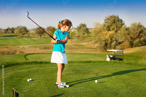 Cute little girl playing golf on a field outdoor