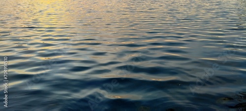 Sunset light reflected in the water with ripples on the surface