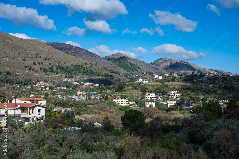 Panoramic view over the rough mountains with houses and blue sky around Cannizzaro- Favare, Italy