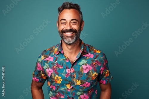 Handsome middle aged man in colorful shirt laughing over blue background