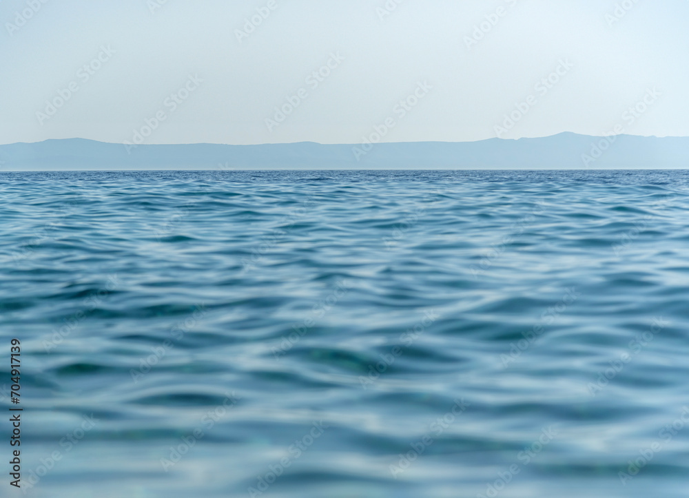 Blue sea, tranquil waves and mist over the water.