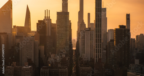 Beautiful Cinematic Aerial Sunset Shot of New York City Skyscrapers and Busy City Streets with Car Traffic. Panoramic Helicopter View of Lower Manhattan Office Buildings