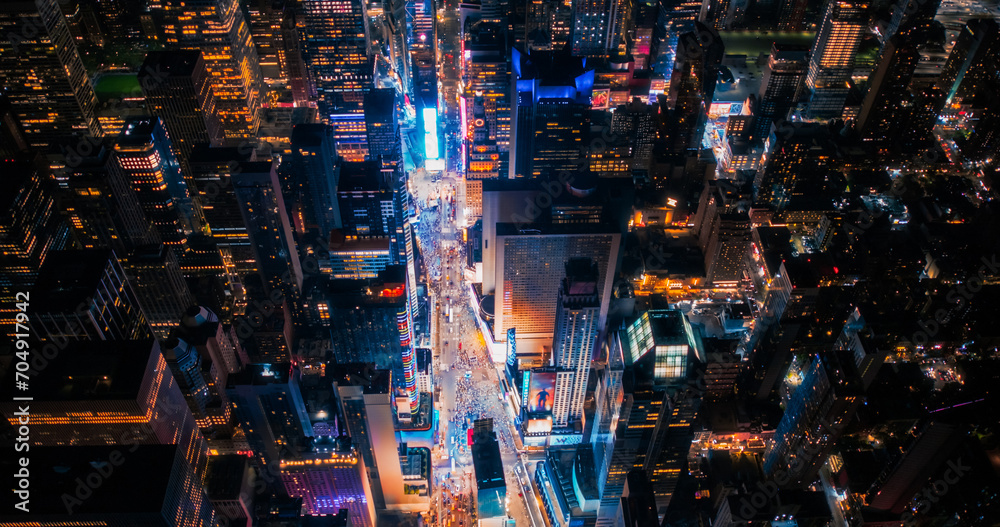 Night Aerial Photo of New York City with Skyscraper Spires and Straight Busy Streets with Cars and Yellow Taxi Vehicles. Lowered Helicopter View of Office Buildings in a Big Urban Center