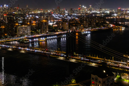 New York City Skyline Aerial Photo from a Helicopter at Night. Famous Skyscraper Buildings with Manhattan Bridge. Busy Diverse Megapolis with Cars, Boats and People Moving Around © Gorodenkoff