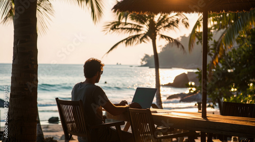 Young digital nomad working at hotel lounge next to beautiful tropical beach. Digital nomad’s lifestyle, Remote job and teleworking concept, Vacation Leave, Travel and work lifestyle. © Davin