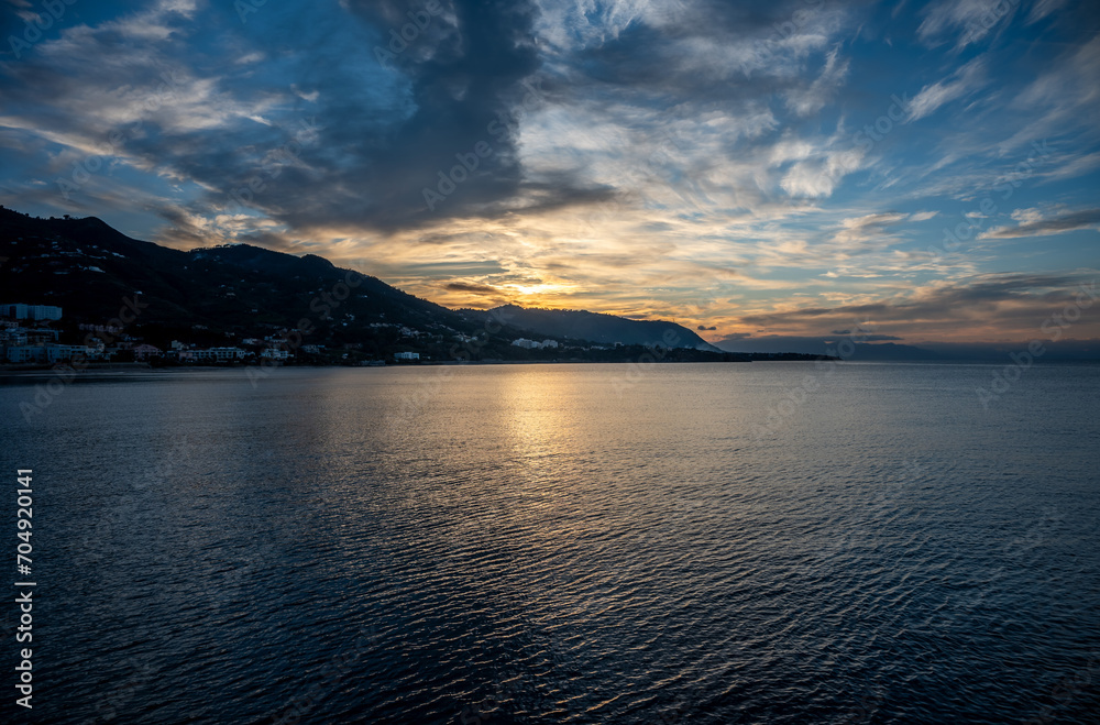 Sunset from the docks over the sea and mountains of the village of Cefalu, Italy