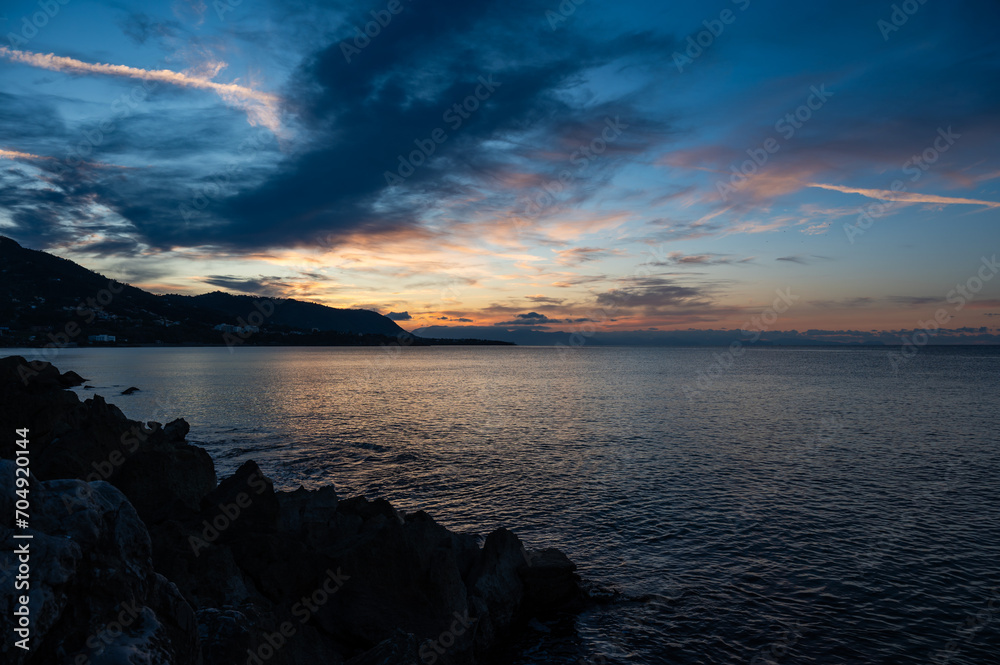 Sunset from the docks over the sea and mountains of the village of Cefalu, Italy