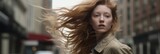 A model turns her head with wind-blown hair, set against a blurred city background, embodying a sense of grace and movement in the midst of the urban hustle.
