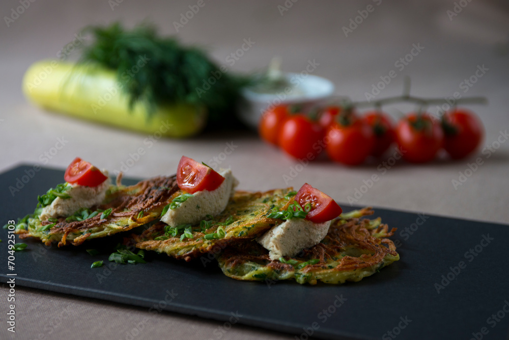 Zucchini pancakes with feta cheese, cherry tomatoes and herbs