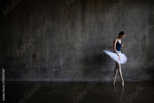 Fototapeta Naklejka Na Ścianę i Meble -  Young ballerina stands leaning against the wall