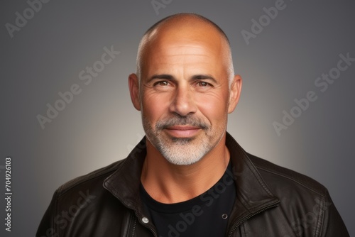 Handsome middle age man in black leather jacket over grey background.