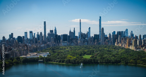 Sunny Weather New York City Aerial Landscape Over Central Park with Midtown Manhattan Skyscrapers. Cinematic Drone View of Urban Skyline with Slightly Cloudy Blue Sky
