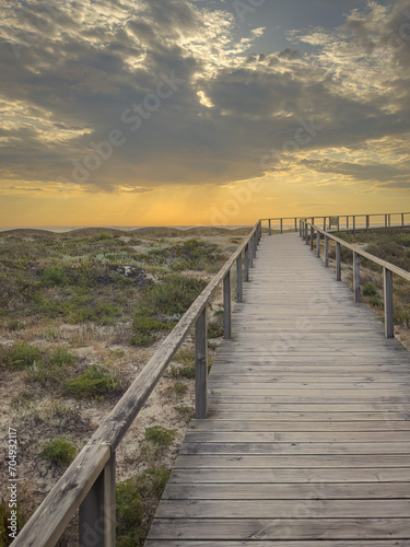 A wood pedestrian walkways, build over a sand dune that is used to give beach access in Furadouro beach, glows at sunset. Ovar, Aveiro, Portugal, Europe © anammarques
