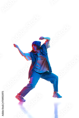 Full-length image of young woman in sportive clothe dancing hip hop isolated over white background in neon light. Concept of contemporary dance, street style, youth, hobby, action, lifestyle