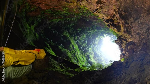 Vertical shot of man inside Algar do Carvao Volcanic tube in Azores, static photo