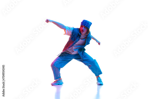 Sportive young woman in casual jeans sportive clothe dancing modern dance isolated over white background in neon light. Concept of contemporary dance, street style, youth, hobby, action, lifestyle