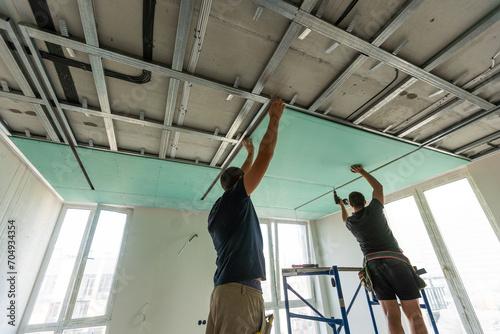 Two workers are mounted ceiling in the new flat photo