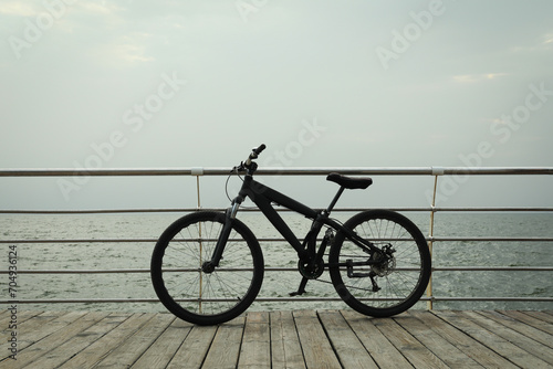 Black bicycle on wooden floor outdoors by the sea