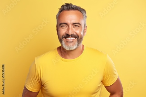 Portrait of handsome mature man in yellow t-shirt on yellow background