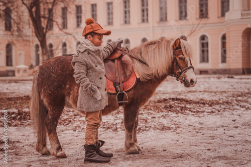 a boy stands next to a pony about to get into the saddle