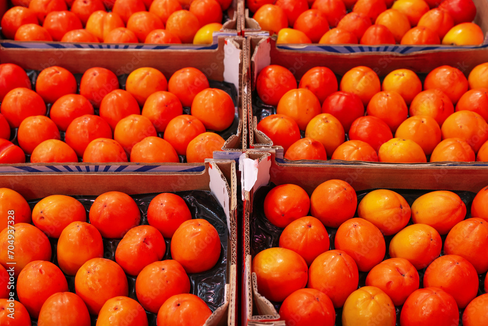 Many fresh persimmons in containers at wholesale market