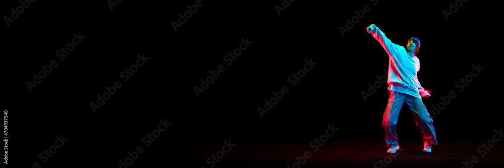 Young girl, hip hop dancer in motion, dancing isolated over black background in neon light. Concept of contemporary dance, street style, youth, hobby, lifestyle. Banner. Empty space to insert text - obrazy, fototapety, plakaty 