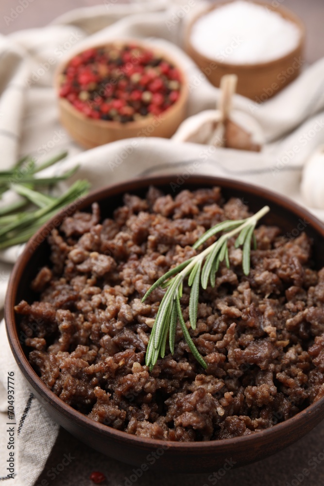 Fried ground meat in bowl and rosemary on table, closeup Fried ground meat in bowl and rosemary on table, closeup