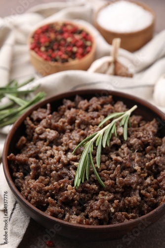 Fried ground meat in bowl and rosemary on table  closeup