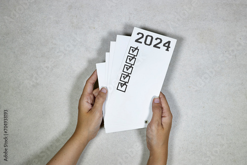 hands holding a card withNew year goals 2024. 2024 goals list.Resolutions, plan, goals, action, checklist, idea concept. New Year 2024 template