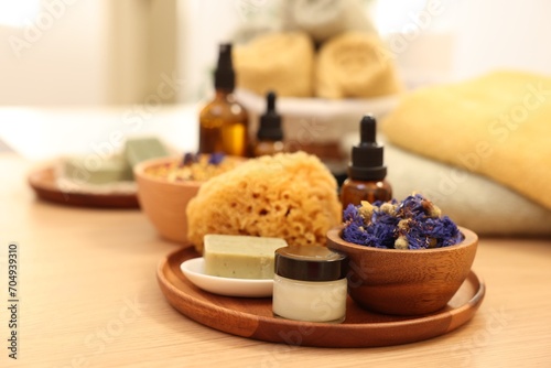 Dry flowers  loofah  soap bar  bottle of essential oil and jar with cream on wooden table indoors. Spa time