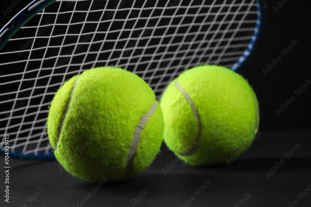 Tennis racket and balls on black background, closeup. Space for text