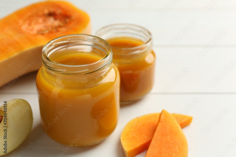 Tasty baby food in jars and ingredients on white table, closeup Tasty baby food in jars and ingredients on white table, closeup