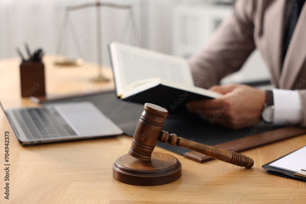 Lawyer reading book at table in office, focus on gavel Lawyer reading book at table in office, focus on gavel