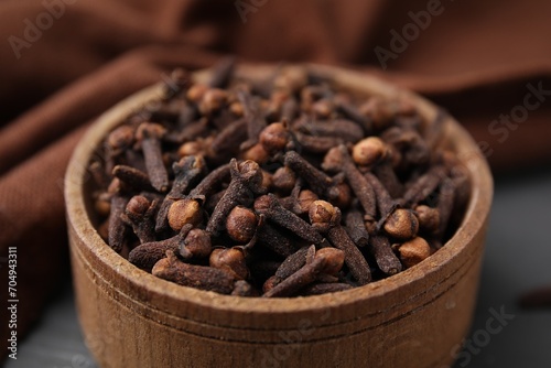 Aromatic cloves in bowl on table, closeup