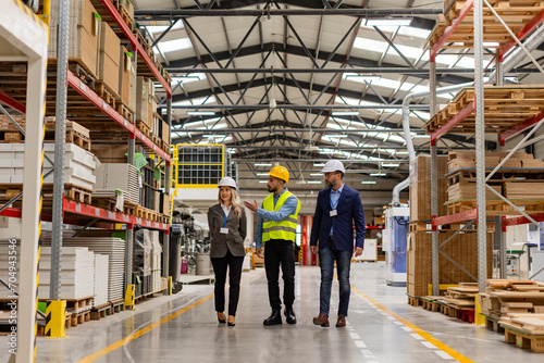 Engineers walking with foreman in modern industrial factory, talking about new production project or investment. Team management in manufacturing facility.