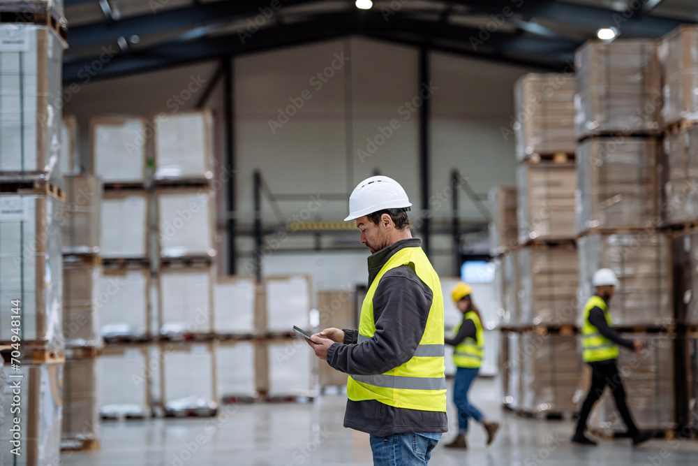 Warehouseman with tablet checking delivery, stock in warehouse. Warehouse manager using warehouse management software, app. Warehouseman with tablet checking delivery, stock in warehouse. Warehouse manager using warehouse management software, app.