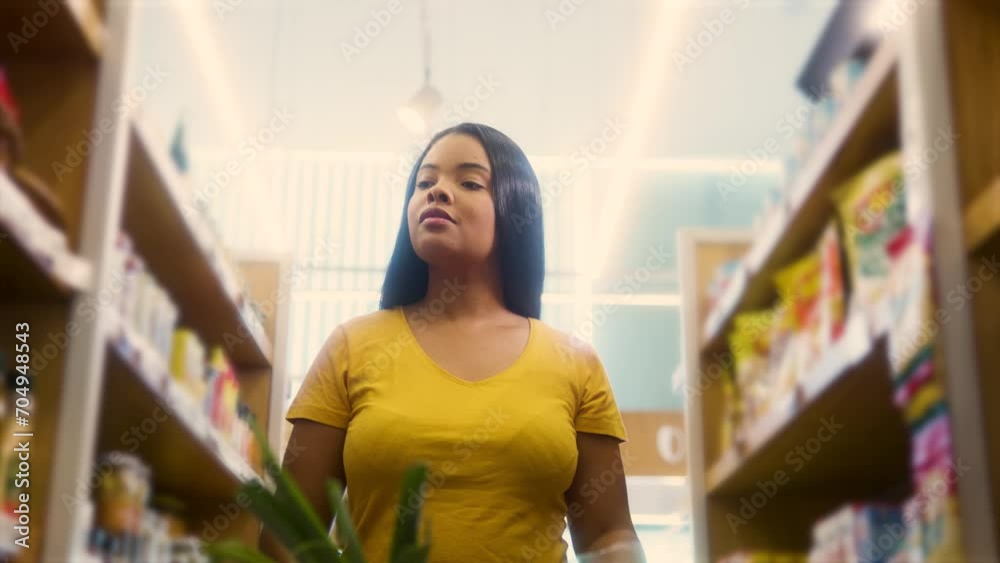 Walking the aisle and shopping. low angle of young black woman with shopping cart Looking for products to buy in grocery store. Walking the aisle and shopping. low angle of young black woman with shopping cart Looking for products to buy in grocery store.