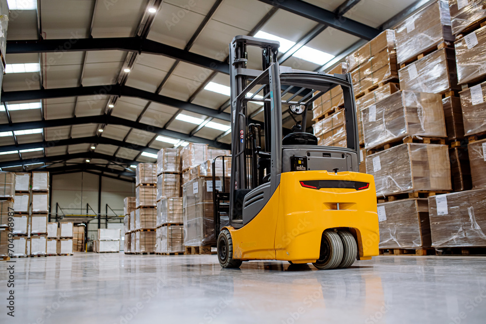 Back view of forklift in warehouse in the middle of stored goods.. Forklift driver preparing products for shipmennt, delivery, checking stock in warehouse.