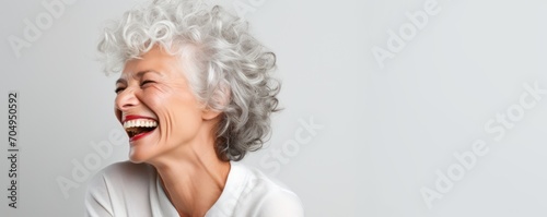 close-up photo portrait capturing the joy of a beautiful elderly senior model woman with grey hair, laughing and smiling with clean teeth. 