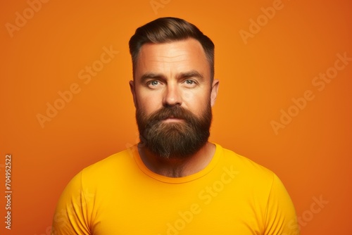 Serious man with beard and mustache looking at camera over orange background