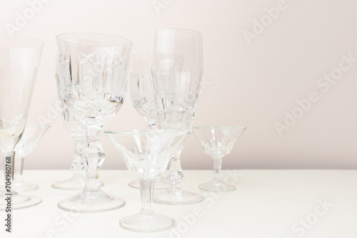 Empty crystal glasses in front of beige background. Place for text.